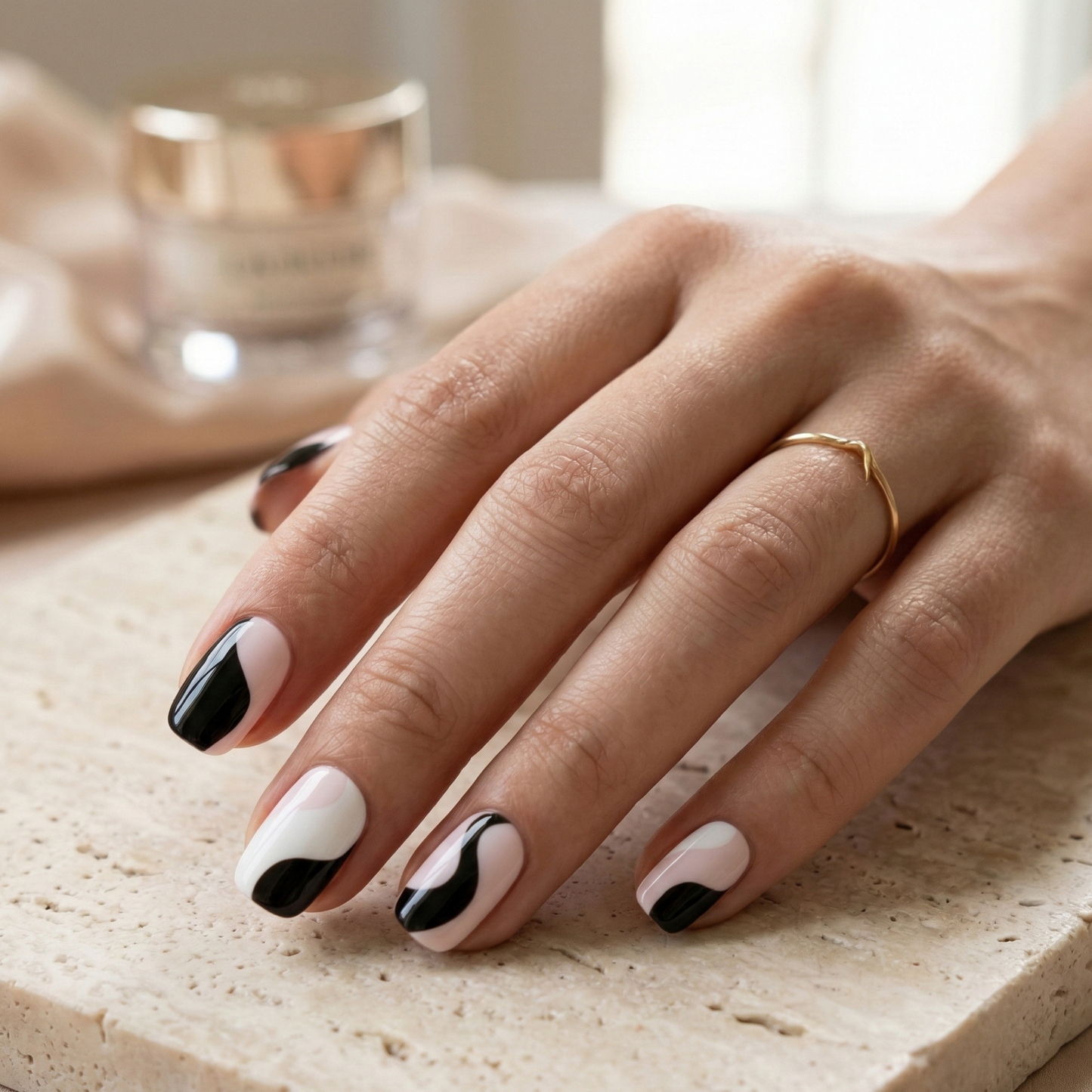 Hand with black and white nail design on a light surface